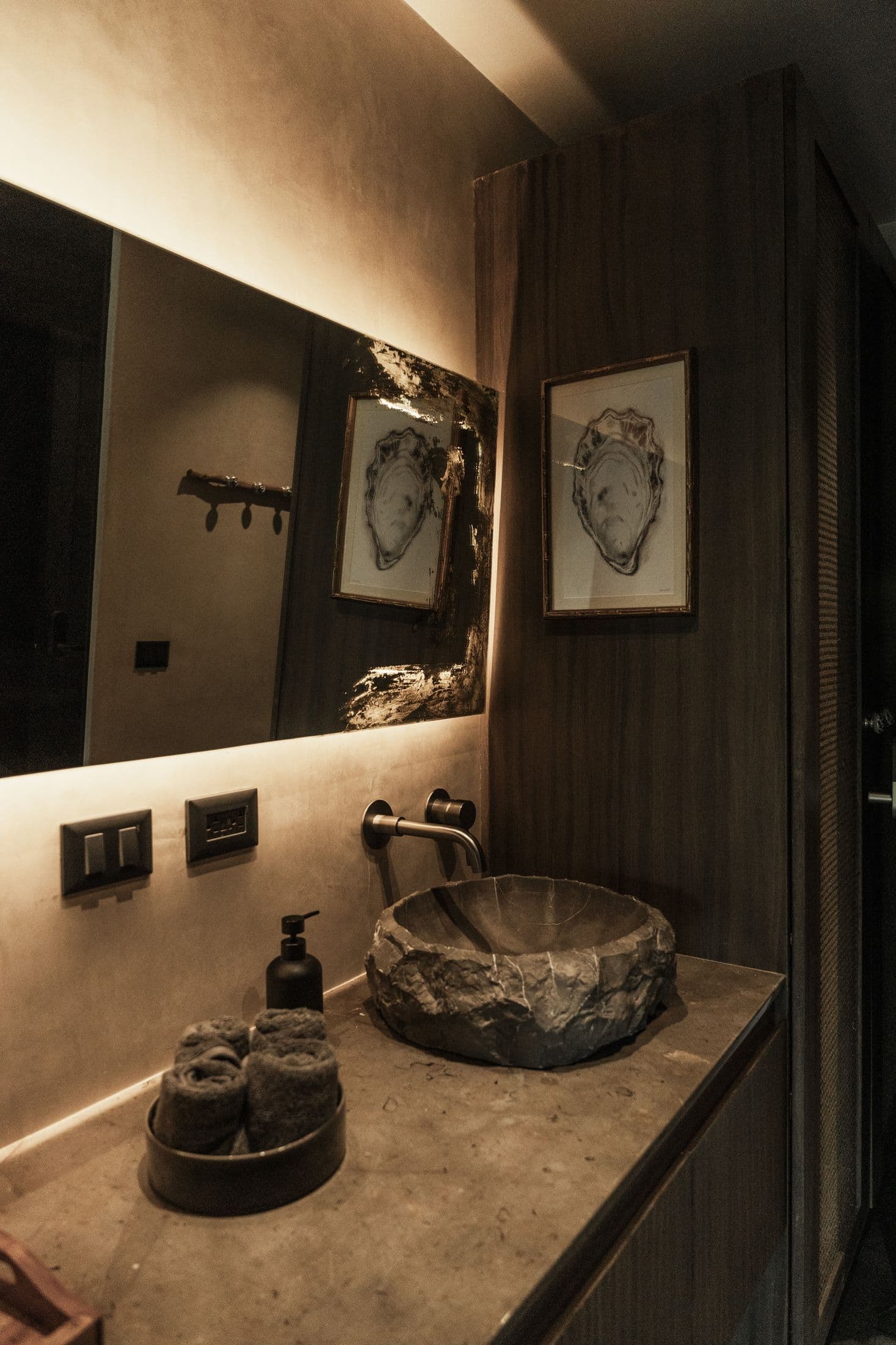 Bathroom vanity with stone basin and backlit mirror